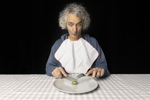 Dominik Müller staunend am Tisch schneidet eine Olive